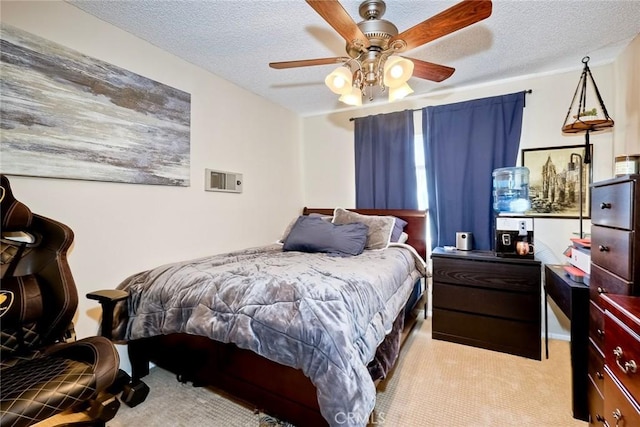 bedroom with ceiling fan, light colored carpet, and a textured ceiling