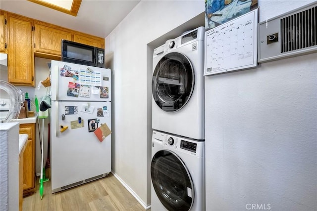 washroom featuring light hardwood / wood-style floors and stacked washer / drying machine