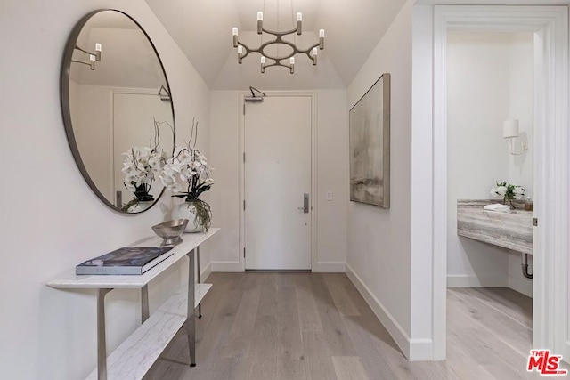 entrance foyer with light hardwood / wood-style flooring, a chandelier, and vaulted ceiling