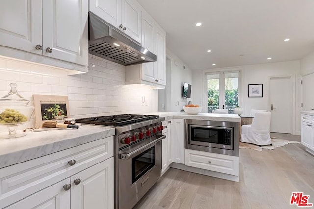 kitchen featuring kitchen peninsula, tasteful backsplash, stainless steel appliances, light hardwood / wood-style floors, and white cabinetry