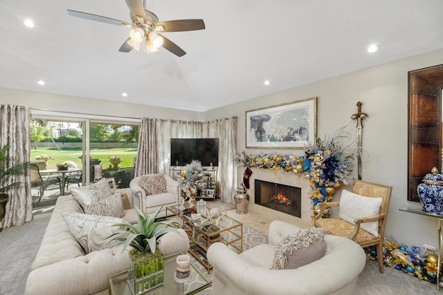 carpeted living room with ceiling fan and a high end fireplace