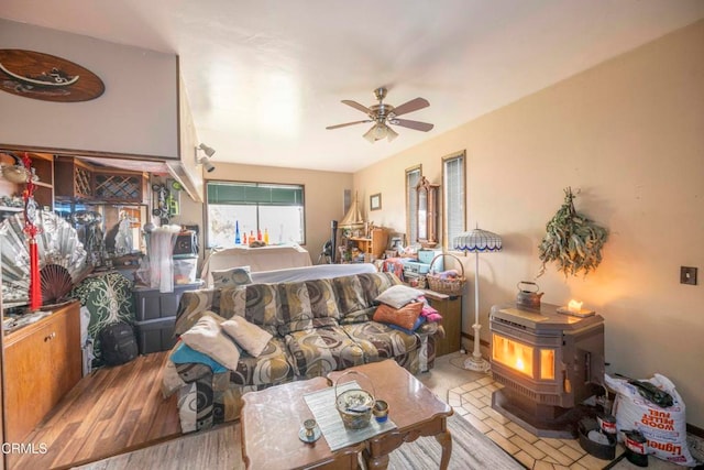 living room with light wood-type flooring, a wood stove, and ceiling fan