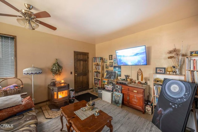 living room featuring a wood stove and ceiling fan