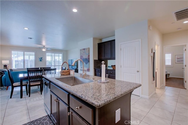 kitchen featuring a center island with sink, visible vents, dishwasher, light stone counters, and a sink