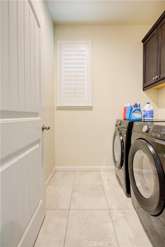 laundry area with light tile patterned floors, washer and clothes dryer, cabinet space, and baseboards