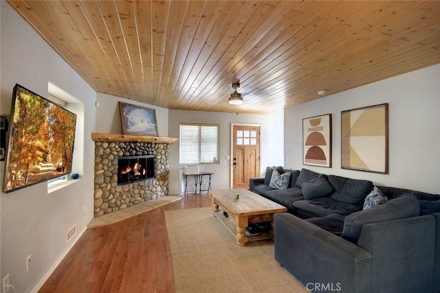 living room featuring wooden ceiling, hardwood / wood-style floors, and a stone fireplace