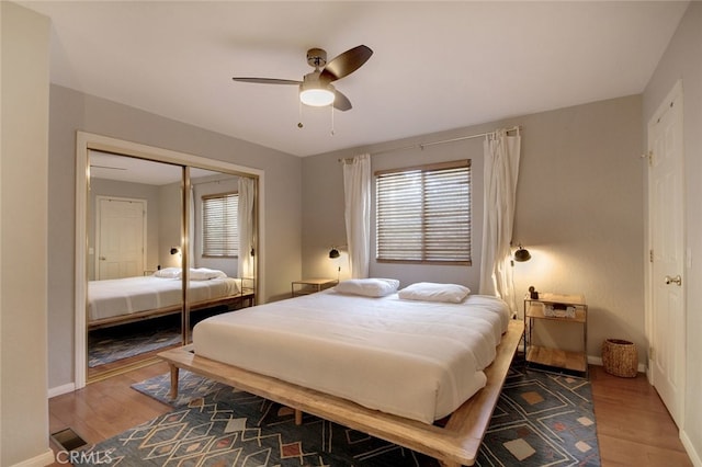 bedroom with ceiling fan, a closet, multiple windows, and wood-type flooring