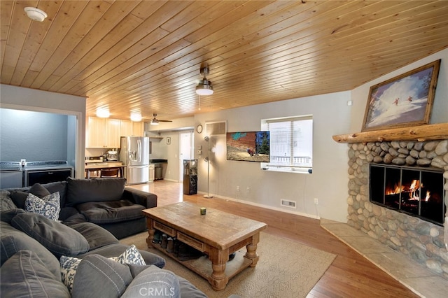 living room with ceiling fan, light hardwood / wood-style flooring, wood ceiling, and a fireplace