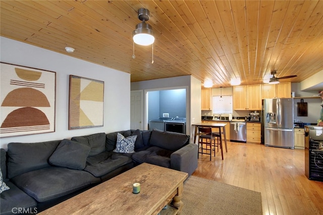 living room with ceiling fan, washing machine and dryer, wood ceiling, and light hardwood / wood-style flooring