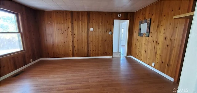 spare room featuring wood walls and wood-type flooring