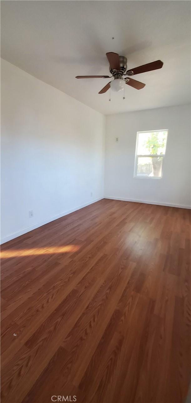 empty room with ceiling fan and dark wood-type flooring