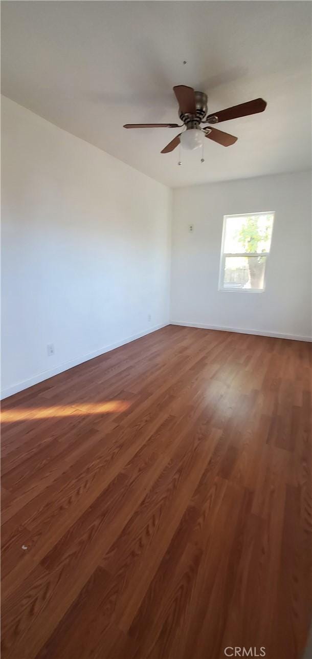 unfurnished room with ceiling fan, baseboards, and wood finished floors