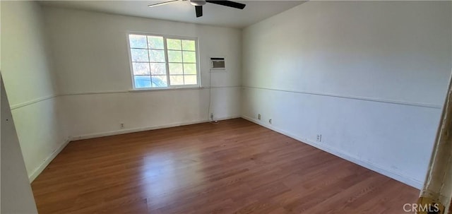 spare room featuring a wall unit AC, ceiling fan, and hardwood / wood-style flooring