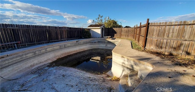 view of swimming pool with an outdoor structure, a storage unit, and a fenced backyard