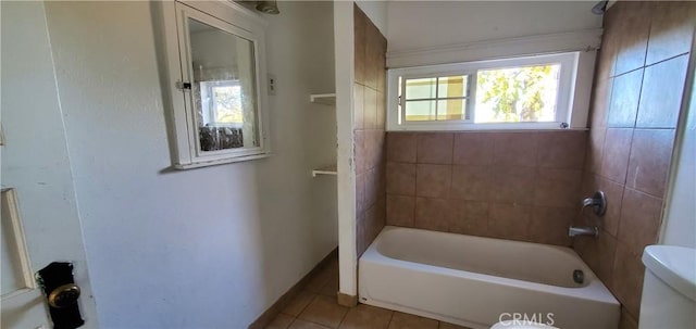 bathroom featuring tile patterned flooring, toilet, and tiled shower / bath