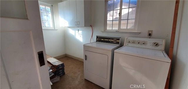 laundry area featuring washer and clothes dryer, light tile patterned flooring, and a healthy amount of sunlight