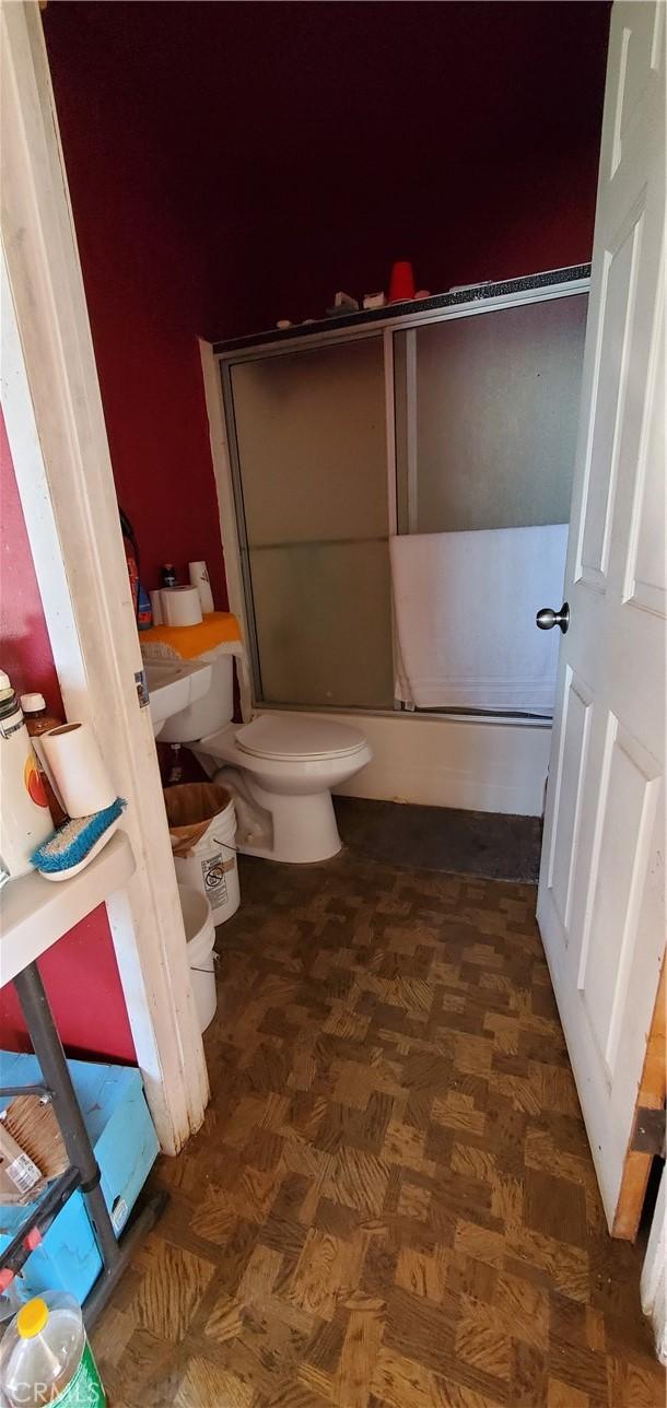 bathroom featuring parquet flooring and toilet