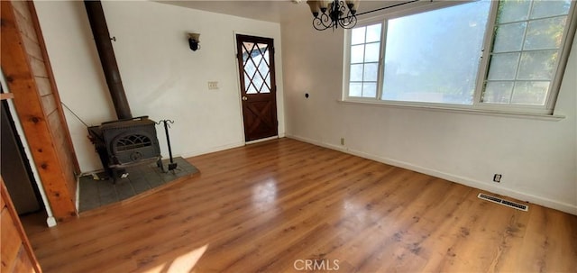 foyer featuring a wood stove, a chandelier, and hardwood / wood-style flooring