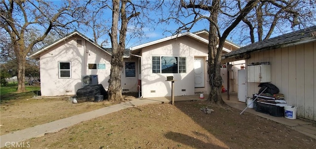 back of property with ac unit, crawl space, and stucco siding