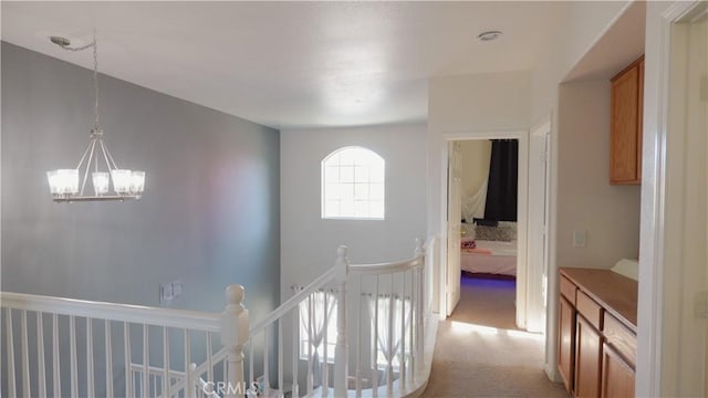 corridor featuring light carpet and an inviting chandelier