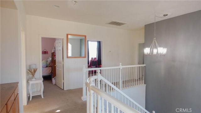 hall with light carpet and a chandelier