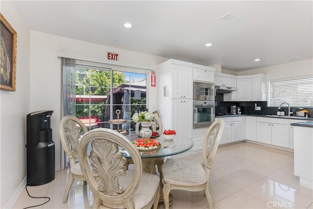 kitchen featuring decorative backsplash, light tile patterned floors, white cabinetry, and plenty of natural light