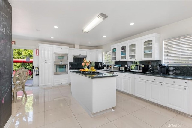 kitchen featuring white cabinetry, sink, a center island, decorative backsplash, and light tile patterned flooring