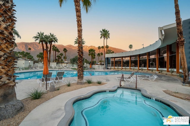 pool at dusk with a mountain view and a patio