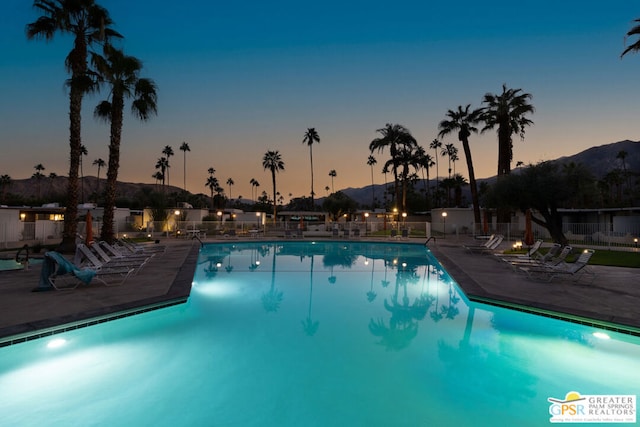 pool at dusk featuring a mountain view and a patio