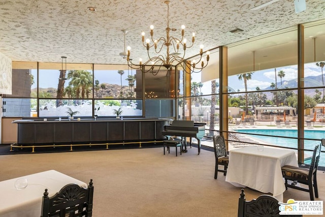 dining area featuring a healthy amount of sunlight, a chandelier, a mountain view, and floor to ceiling windows