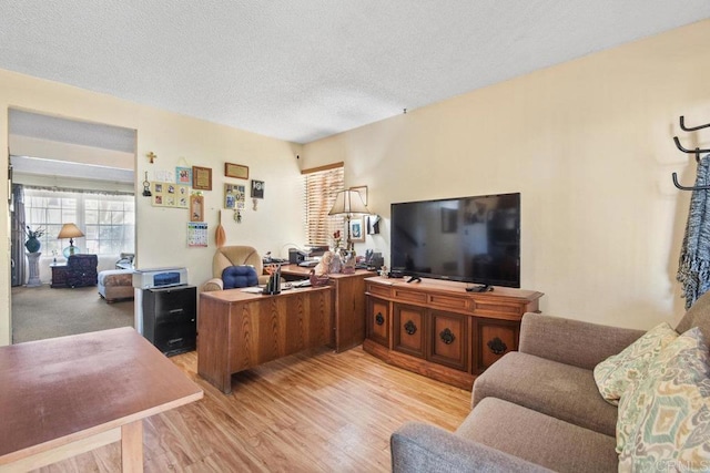 home office with light wood-type flooring and a textured ceiling