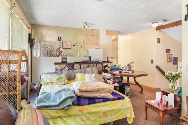 carpeted bedroom with freestanding refrigerator and a textured ceiling