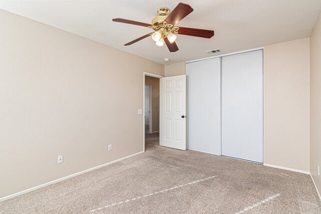 unfurnished bedroom with ceiling fan, a closet, and carpet floors