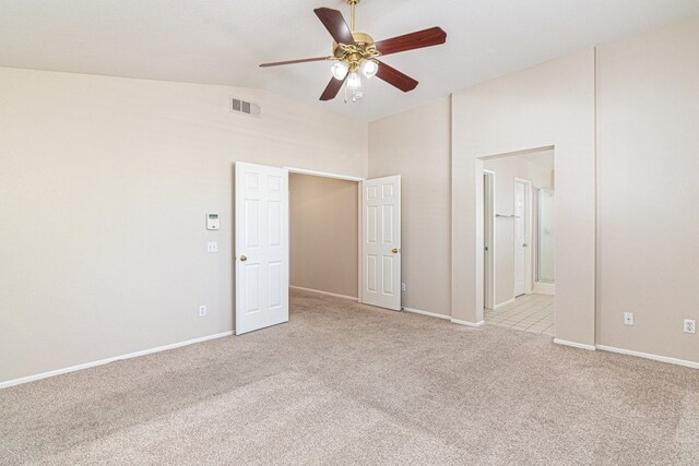 unfurnished bedroom with light colored carpet, vaulted ceiling, ceiling fan, and ensuite bathroom