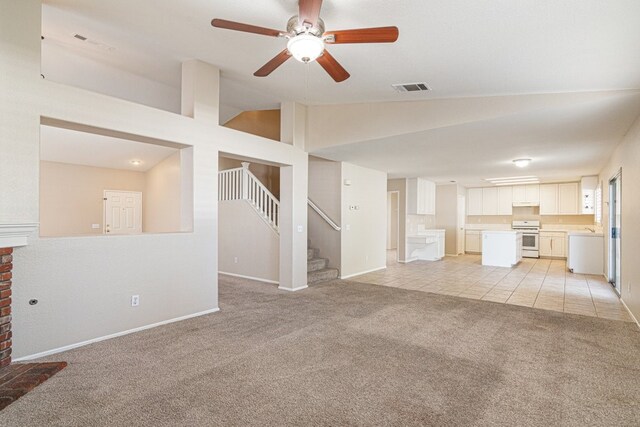 unfurnished living room featuring ceiling fan, light colored carpet, and vaulted ceiling