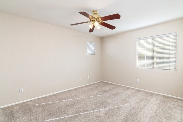 carpeted spare room featuring ceiling fan and a healthy amount of sunlight