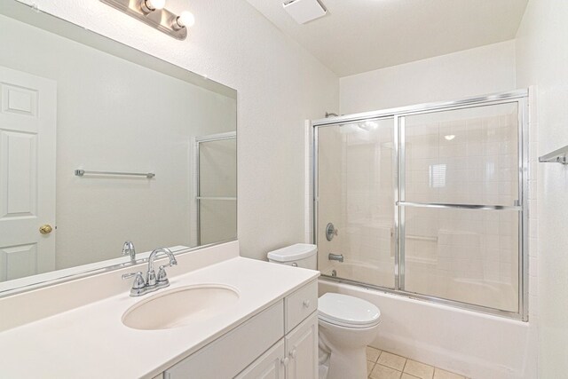 full bathroom featuring tile patterned floors, vanity, enclosed tub / shower combo, and toilet