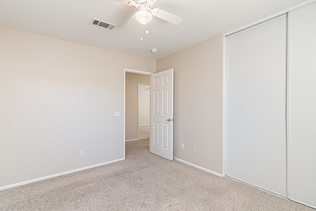 unfurnished bedroom featuring ceiling fan, a closet, and light colored carpet