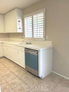 kitchen with dishwasher, white cabinets, light tile patterned floors, and sink