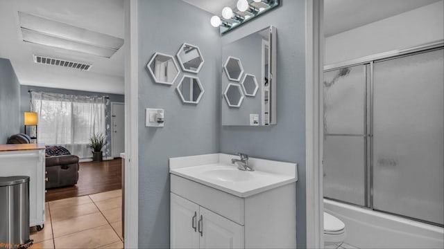 full bathroom with tile patterned flooring, vanity, combined bath / shower with glass door, and toilet