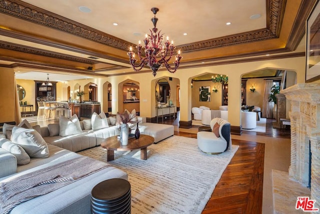 living room with a chandelier, ornamental molding, hardwood / wood-style floors, and a tray ceiling