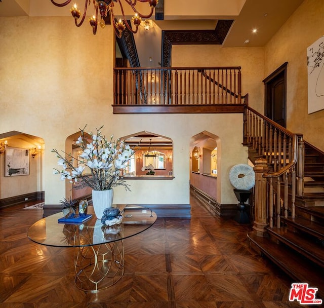 interior space with a high ceiling, an inviting chandelier, and dark parquet flooring