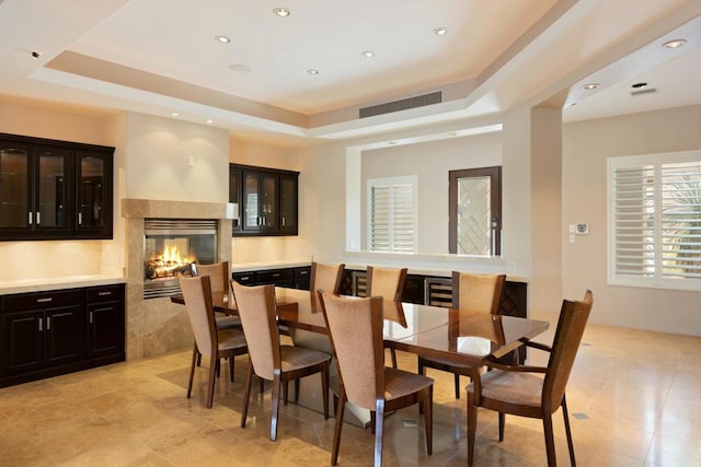 dining room with a tray ceiling and a multi sided fireplace