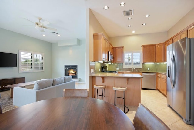 kitchen with a kitchen bar, stainless steel appliances, tasteful backsplash, and plenty of natural light