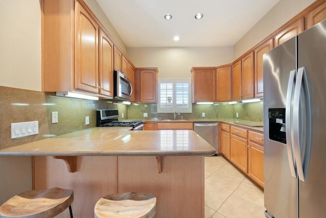 kitchen with a kitchen breakfast bar, kitchen peninsula, sink, and appliances with stainless steel finishes