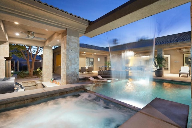 pool at dusk with ceiling fan, a patio, and a hot tub