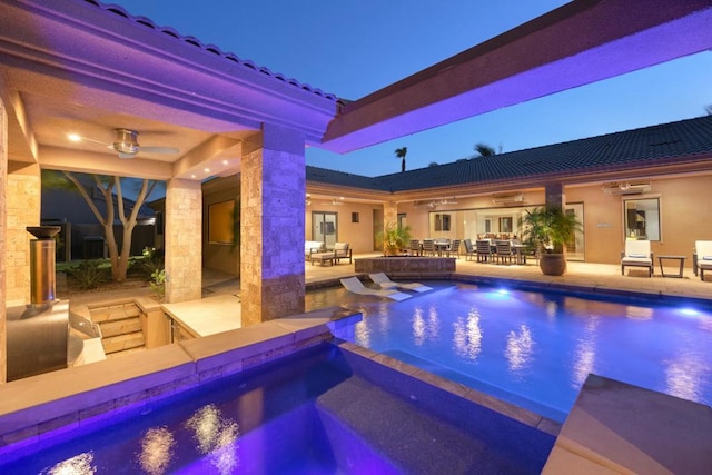 pool at dusk featuring an in ground hot tub, ceiling fan, and a patio area