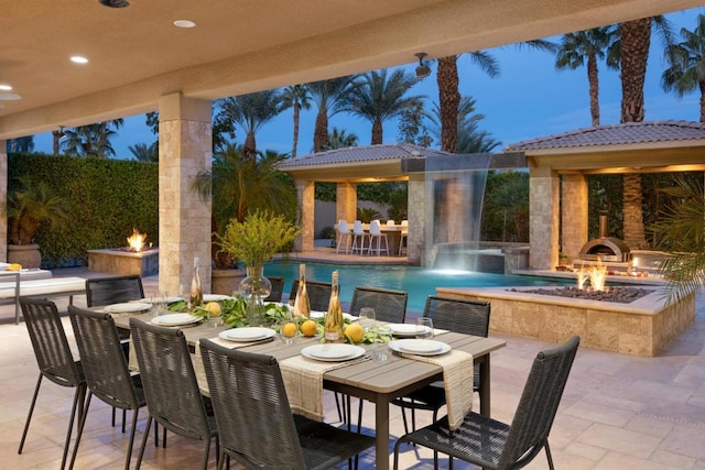 patio terrace at dusk with a fire pit and pool water feature