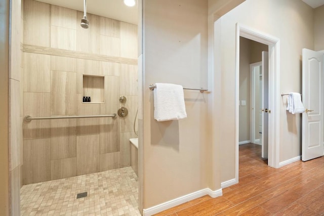 bathroom with a tile shower and hardwood / wood-style flooring