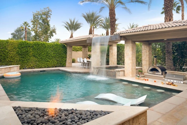 view of pool with area for grilling and an in ground hot tub